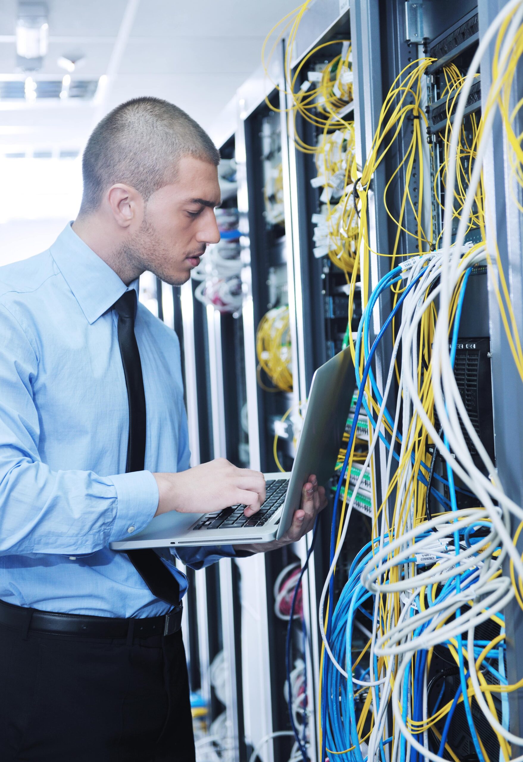 businessman with laptop in network server room